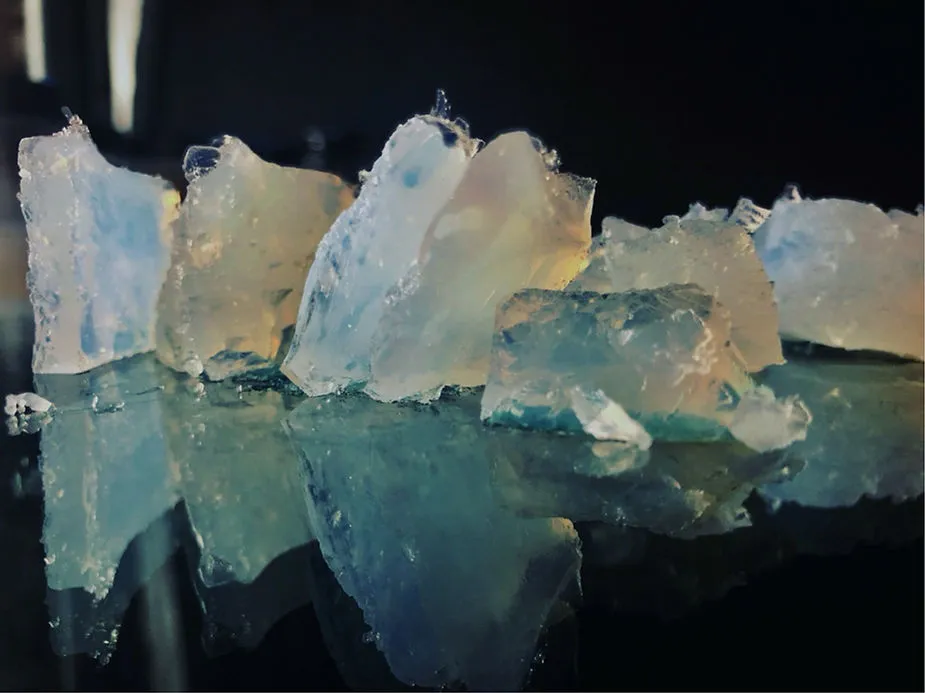 Close-up of translucent crystals with blue and clear hues on a reflective surface.