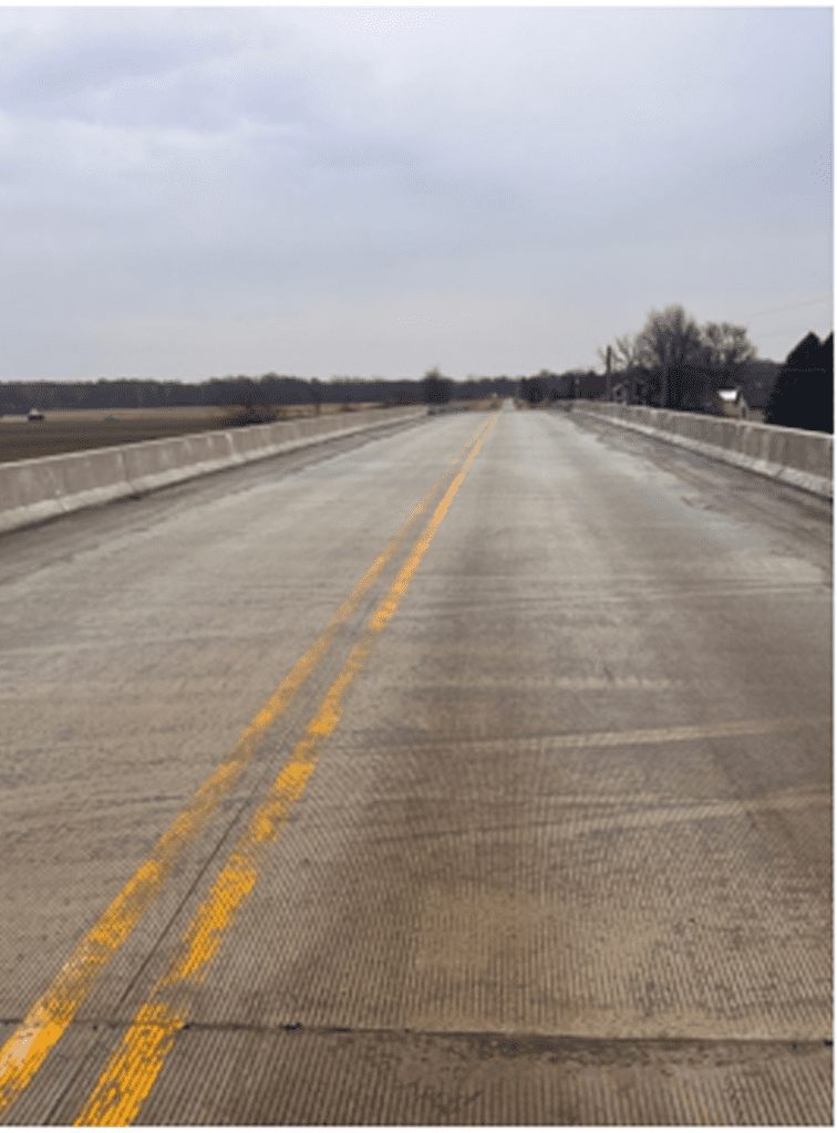 Empty concrete road stretching into the horizon on a cloudy day.