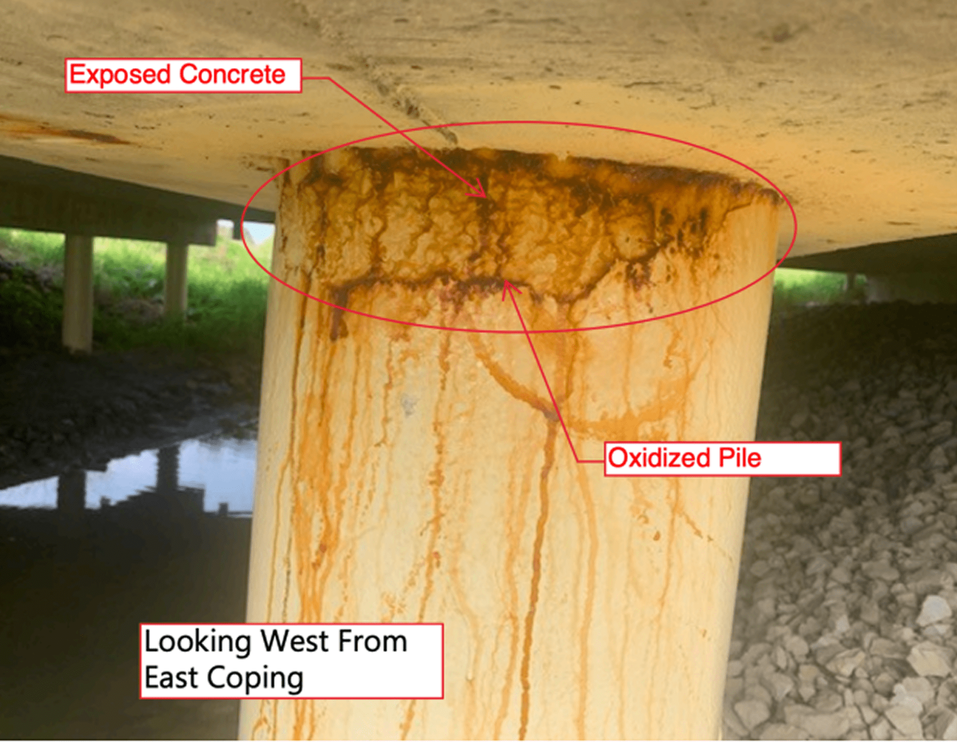 Rust stains on a concrete bridge pier supporting a beam.