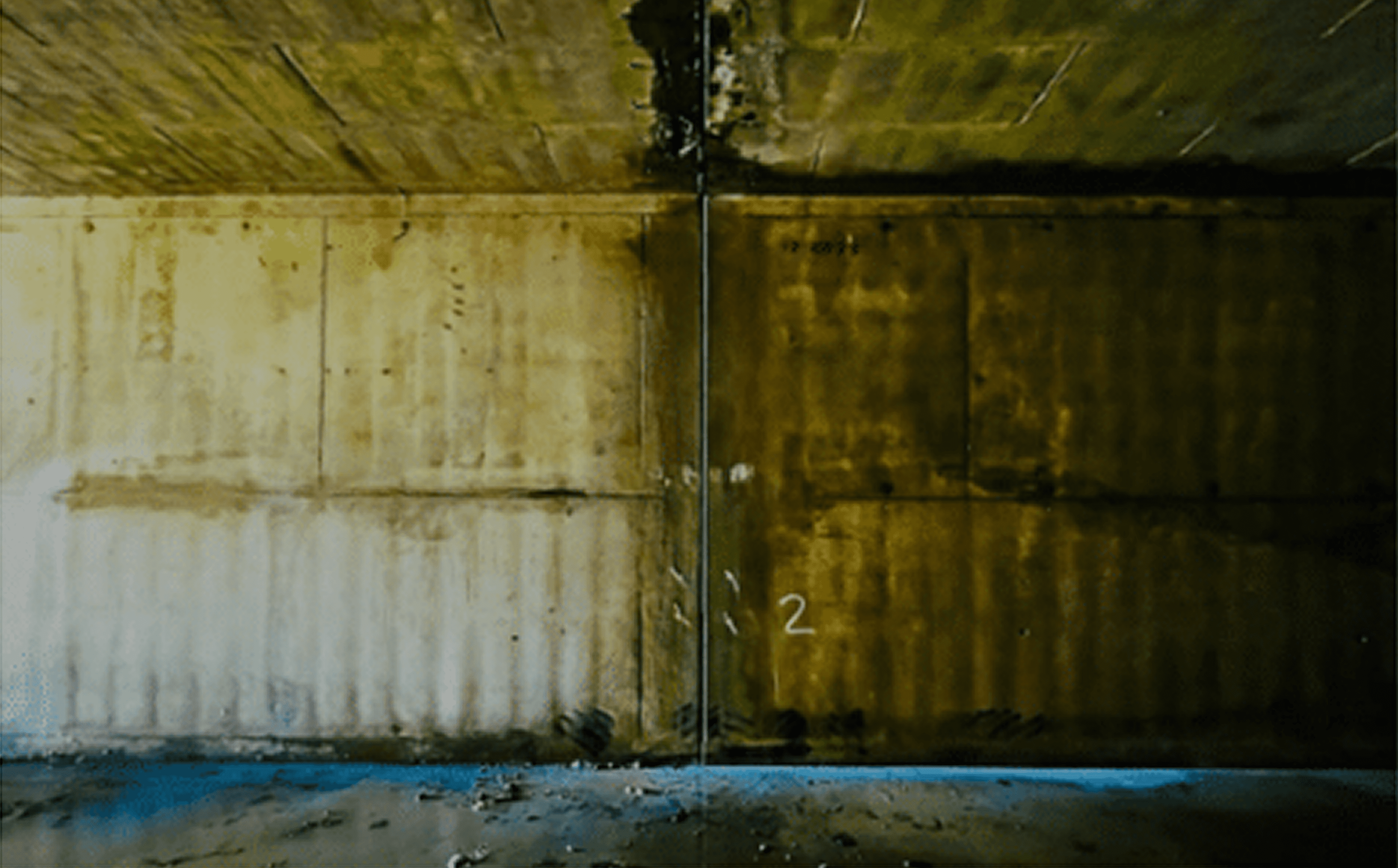 Wall with faded graffiti numbers under a concrete ceiling.