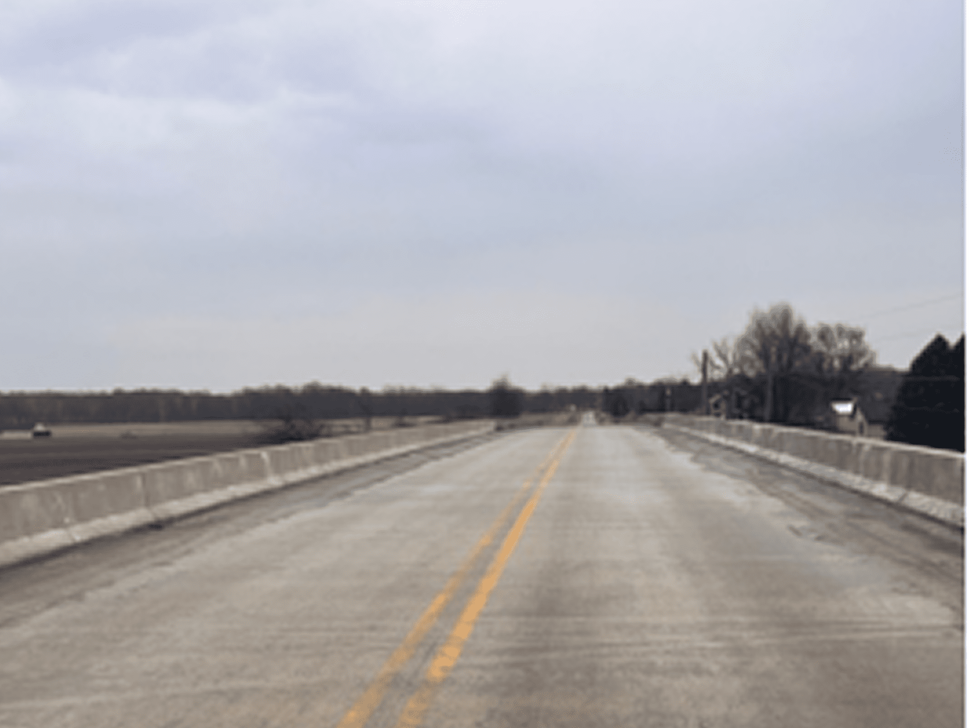 Empty rural road stretching under an overcast sky.