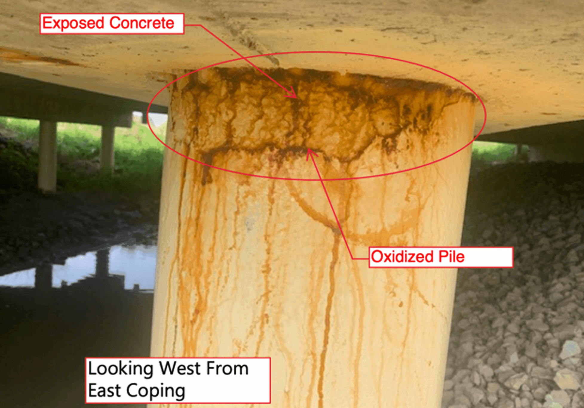 Rust stains on a concrete bridge pier supporting a beam.
