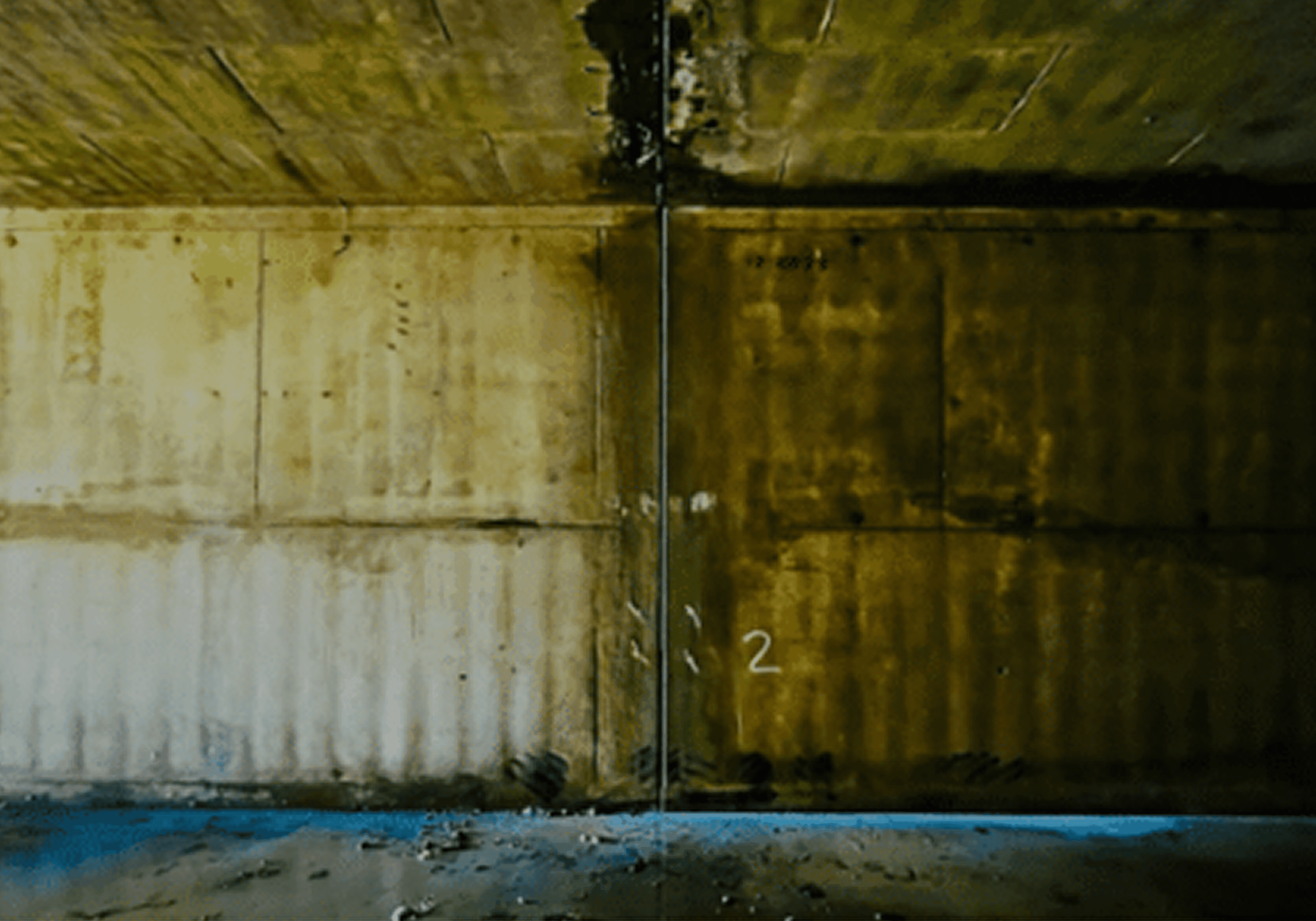 Wall with faded graffiti numbers under a concrete ceiling.