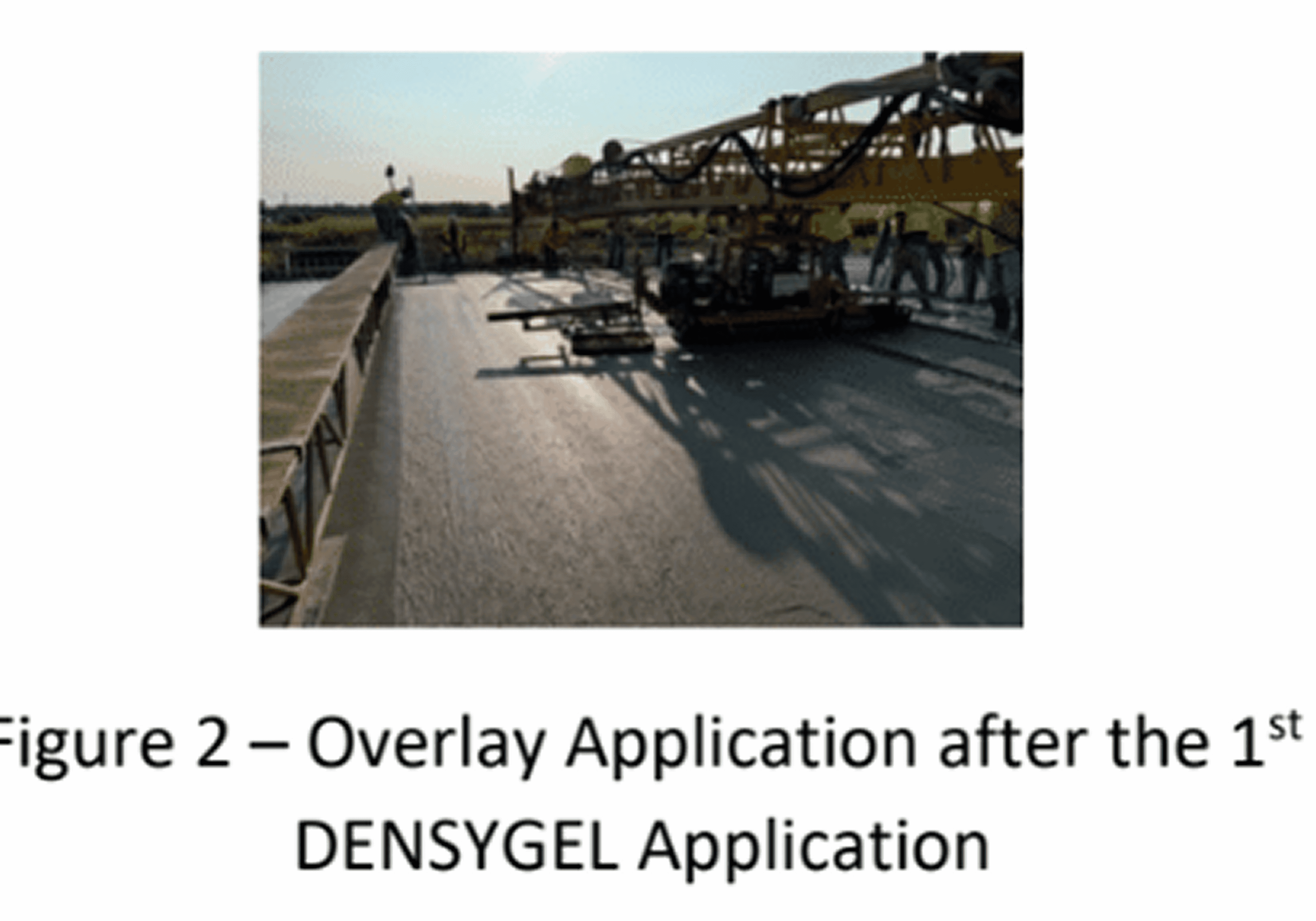 Construction crew applying overlay on a large flat surface at sunset.