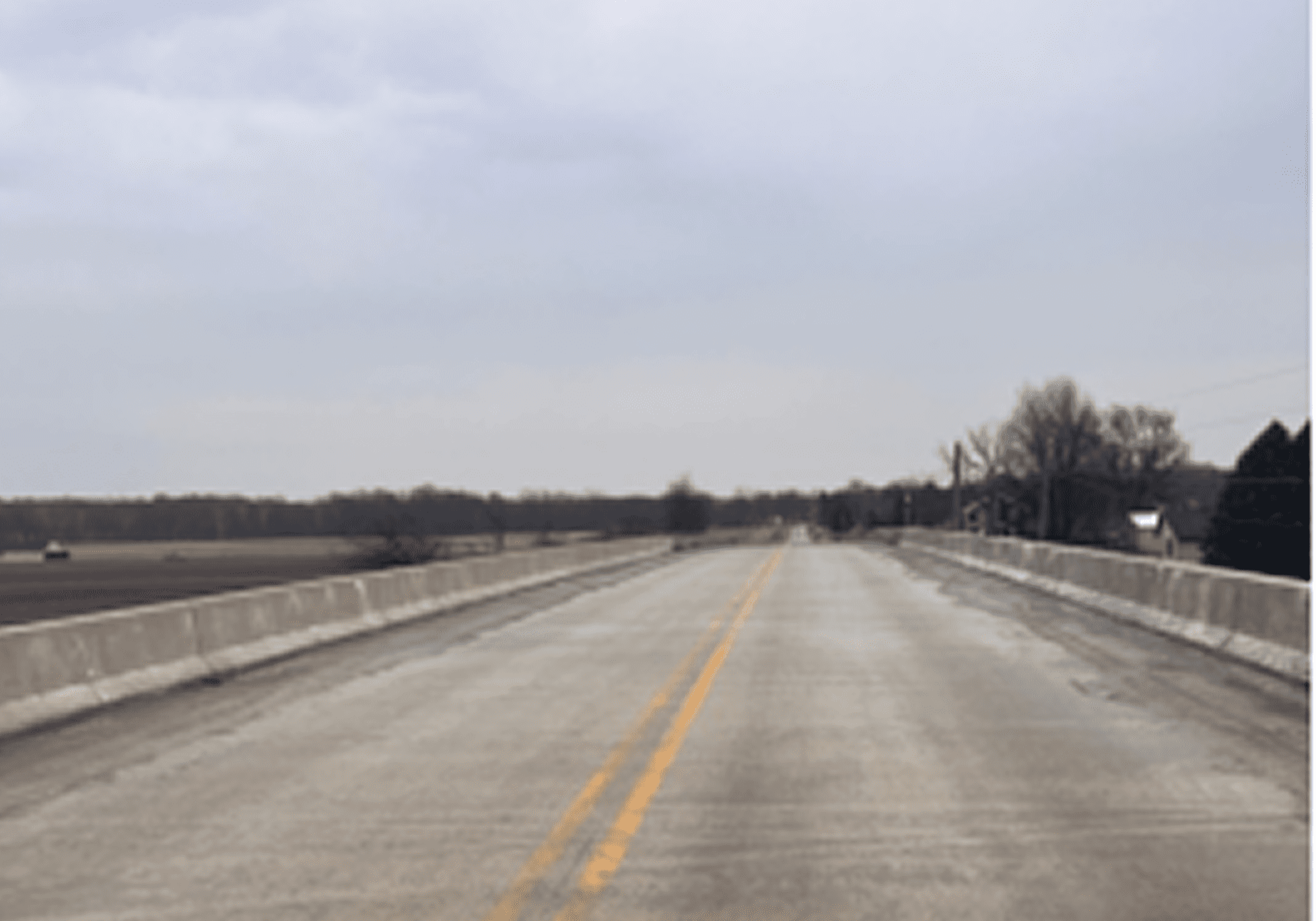 Empty rural road stretching under an overcast sky.